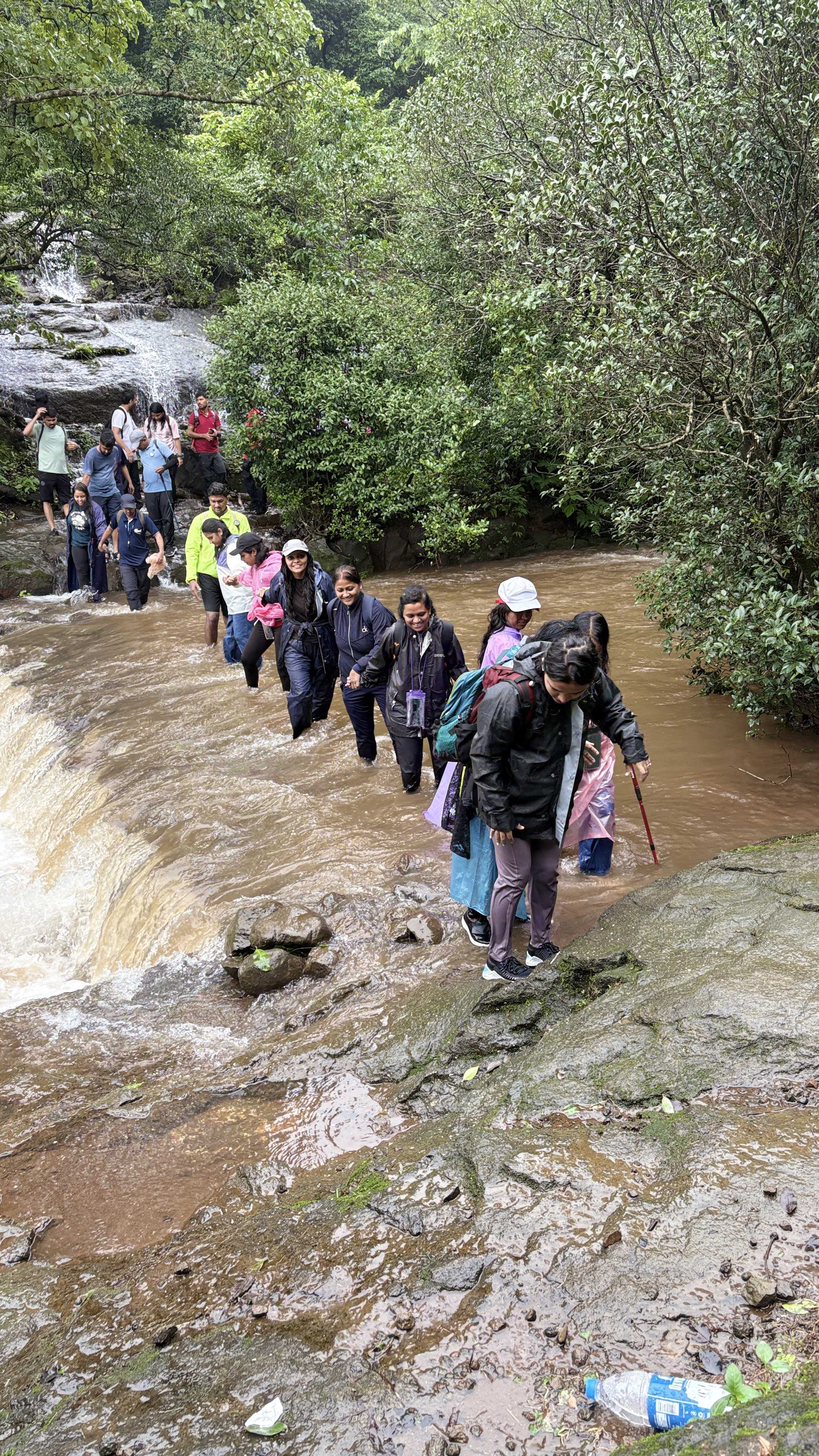 रांगेत उभा राहून नदी ओलांडणारा ग्रुप